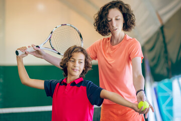 Dark-haired kid having a tennis workout with his female coach