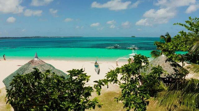 Tropical island in the ocean with palm trees on white sand beach. Daco island, Philippines. Summer and travel vacation concept