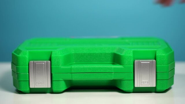 Man opens toolbox of toolkit of many different wrench instruments, tools and screwdrivers. Display of auto repair or household tools laying in green plastic case toolbox