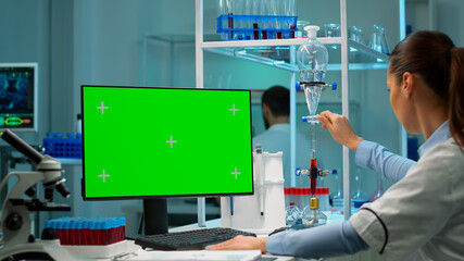 Microbiology scientist typing on keyboard works with green chroma key screen pc developing vaccine,...