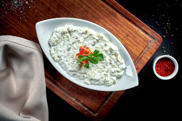 Traditional Arabian eggplant dish Baba Ghanoush with olive oil and herbs in white yogurt. Wood...