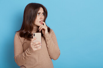 Pensive dark haired European woman thinking how to answer on message, looking aside thoughtful and...