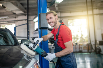 Man professionally polishing gray car in garage