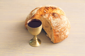 Chalice of wine and bread on wooden background