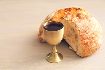 Chalice of wine and bread on wooden background