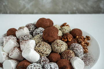 truffles with cocoa, coconut and sesame seeds with chocolate and marshmallows, delicious dessert on a white background
