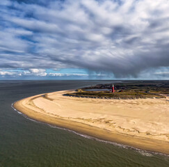 Aerial image of the dutch island of Texel with sand beach, dunes and red light house with rain...