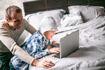 Father and boy play computer games at home together. son chooses a gift f in an online store....