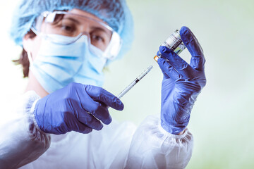 Vaccination, doctor in protective clothes with syringe and ampule - 418671689