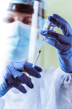 Vaccination, doctor in protective clothes with syringe and ampule