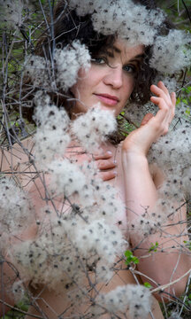 Portrait of a beautiful young sensual brunette woman standing behind clematis vitalba and enjoying her life and nature