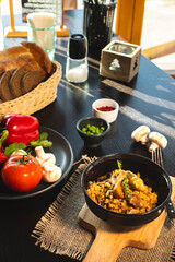 Pearl barley risotto or orzotto with mushrooms in dark bowl on wooden background. Selective focus.