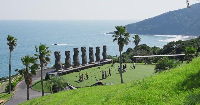 Wide angle view of Moai statues at Sun Messe Nichinan along the beautiful coast in Miyazaki, Japan. Blue ocean and green grass in summer day at Miyazaki.