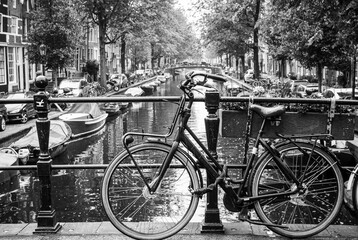 Amsterdam, Holland, May 12 2018: Old bicycle parked on a canal bridge in Amsterdam - obrazy, fototapety, plakaty