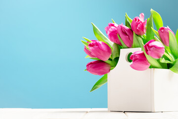 Bunch of pink tulips in white box on wooden table. Flat lay with copy space, Birthday gift. Valentines 8 March Women's or Mothers Day celebration greeting card or web floral banner. Spring