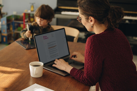 Woman working from home with son using tablet