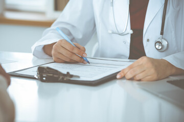 Unknown woman-doctor consulting patient and using clipboard with a medication history record. Medicine concept