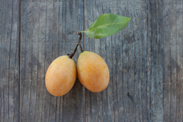 Fresh ripe Sweet Yellow Marian Plum or Plum Mango Thai people call Ma Yong Chit bunch place on wooden table.