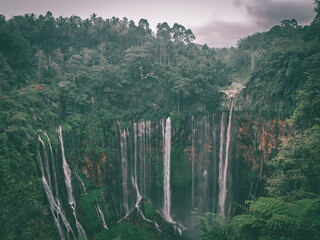 The waterfall is surrounded by dense forest covered with thick clouds, Lumajang, Indonesia Panoramic