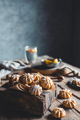 Small custard cakes in wooden box and cup of coffee on brown wooden table