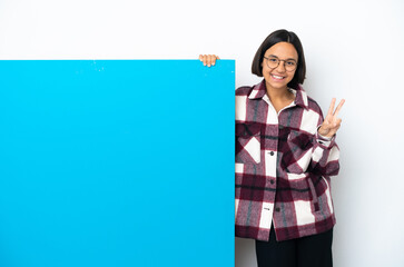 Young mixed race woman with a big blue placard isolated on white background smiling and showing victory sign