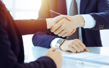 Obraz na płótnie Canvas Businesspeople or lawyers shaking hands finishing up meeting or negotiation in sunny office. Business handshake and partnership
