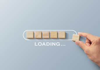 Loading, reboot, refresh or mindset concept. Hand putting wooden blocks in progress bar on gray...