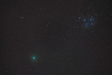 Obraz na płótnie Canvas comet atlas meets the pleiades in the deep sky at night