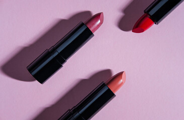 Set of lipsticks on light pink background.