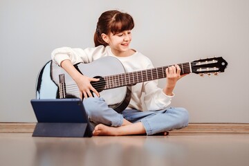 Niña tomando clases de guitarra online por la tablet