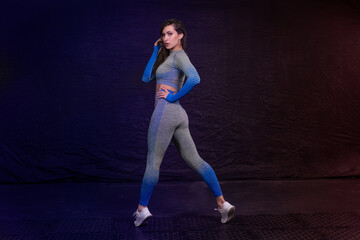girl in fitness clothes posing stood up on socks. dark background