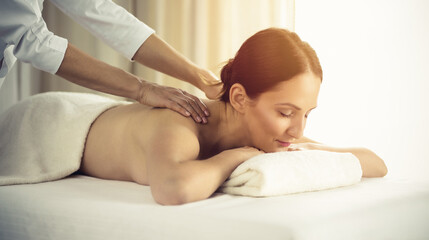 Fototapeta na wymiar Pretty brunette woman enjoying procedure of back massage in spa salon. Beauty concept