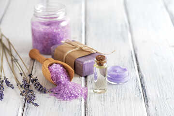 Obraz na płótnie Canvas Lavender spa products on an old white wooden table. Body care products with lavender; oil, salt, cream, soap and dried lavender flowers. Selective focus.
