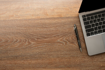 Wood office desk table with laptop computer and pen. Top view with copy space, flat lay.