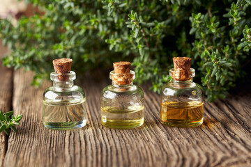 Three bottles of essential oil with fresh thyme