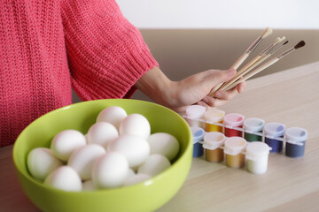 White eggs in green bowl ready to be painted by girl in pink sweater for Easter. Preparing for Easter concept