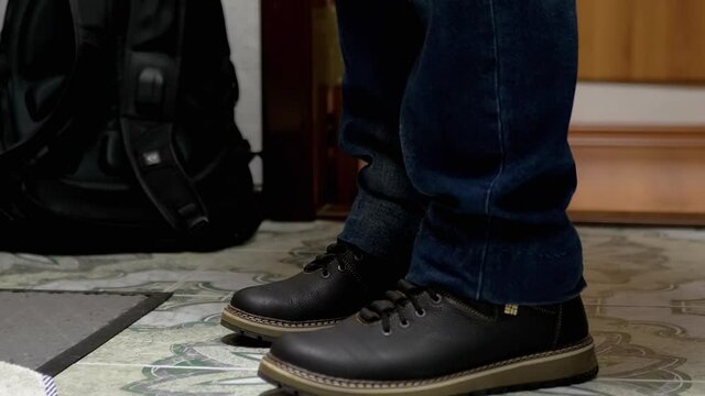 Male Feet in Leather Boots, Shoes, Blue Jeans with a Backpack. 4K