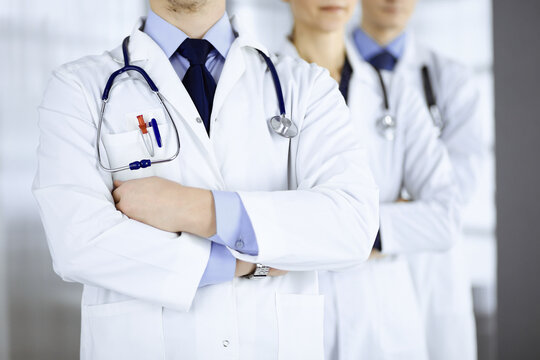 Group of modern doctors standing as a team with crossed arms and stethoscopes in hospital office. Physicians ready to examine and help patients. Medical help, insurance in health care, best desease