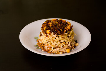Famous traditional Arabic, Egyptian dish - Koshari. National Kushari in a white plate on dark wooden background