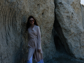 Beautiful woman in a sweater near the rocks in nature and glasses on her face