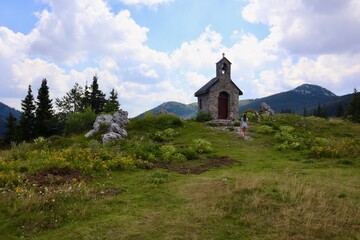 Fototapeta na wymiar Eine kleine Kapelle auf einer Wiese in Kroatien und im Hintergrund ein schöner, bewölkter, blauer Himmel.
