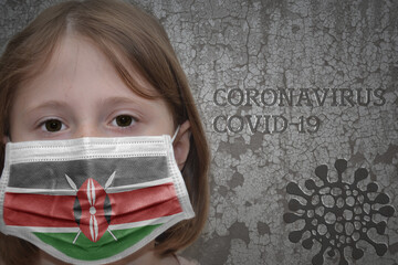 Little girl in medical mask with flag of kenya stands near the old vintage wall with text coronavirus, covid, and virus picture.