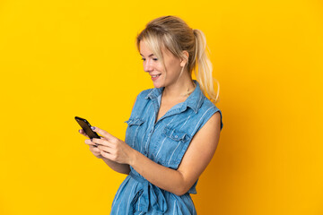 Young Russian woman isolated on yellow background sending a message or email with the mobile