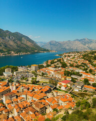 Fototapeta na wymiar Colorful landscape with orange roofs of old town, boats and yachts in marina bay, sea, mountains