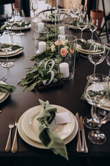 Wedding banquet. The festive table is served with plates with napkins and name cards, glasses and cutlery, and decorated with flower arrangements and candles