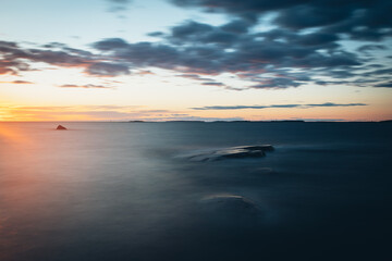 Obraz premium Scenic long exposure sunset over rocks the sea in Faboda, Finland