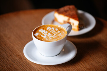 cup of coffee latte with a cake in the background