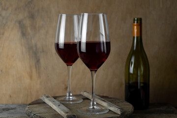 Two glasses of red wine. The bottle of wine is on the table. Wine background. Still life. Alcoholic drink in a glass. Wooden background