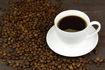 Fototapeta premium Black coffee in white ceramic cup and coffee bean on wooden background.