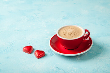 Cup of coffee and heart shaped candies on blue